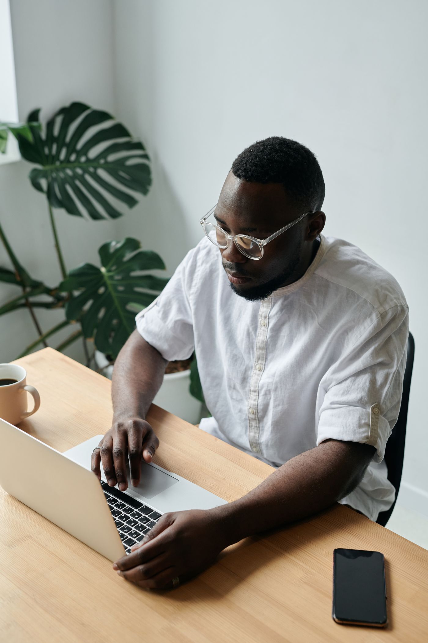A professional in a white shirt working on a laptop in a modern office