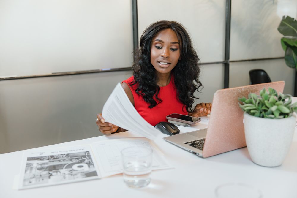 An executive assistant working with documents, laptop and phone